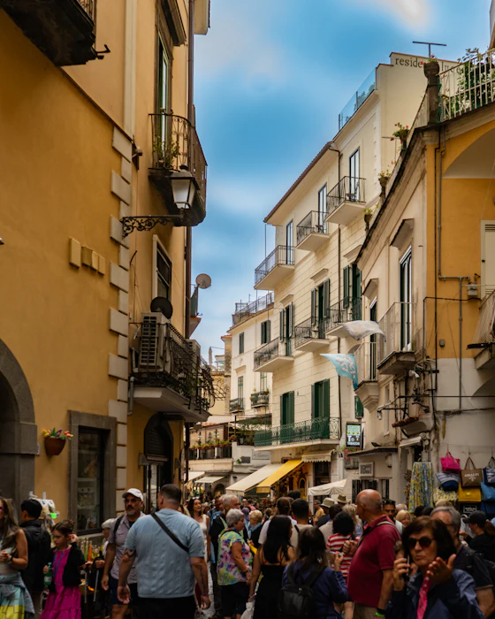 Una via di un centro storico italiano, con negozi e passanti