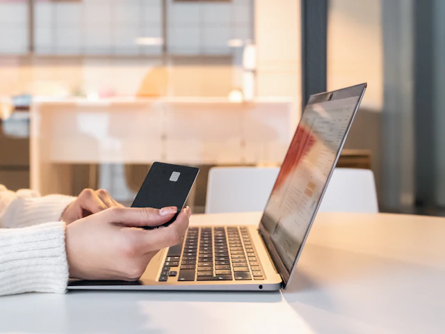 Una persona con una carta di pagamento davanti al computer portatile